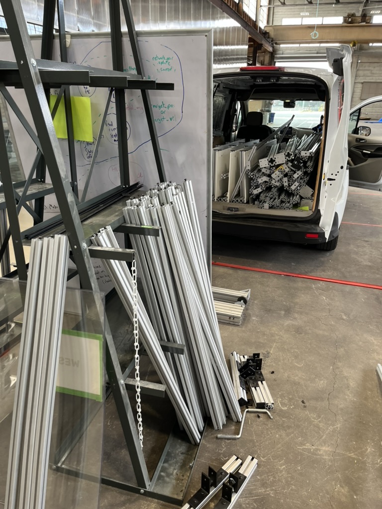 A cart stacked with extrusion profiles parked beside the open van