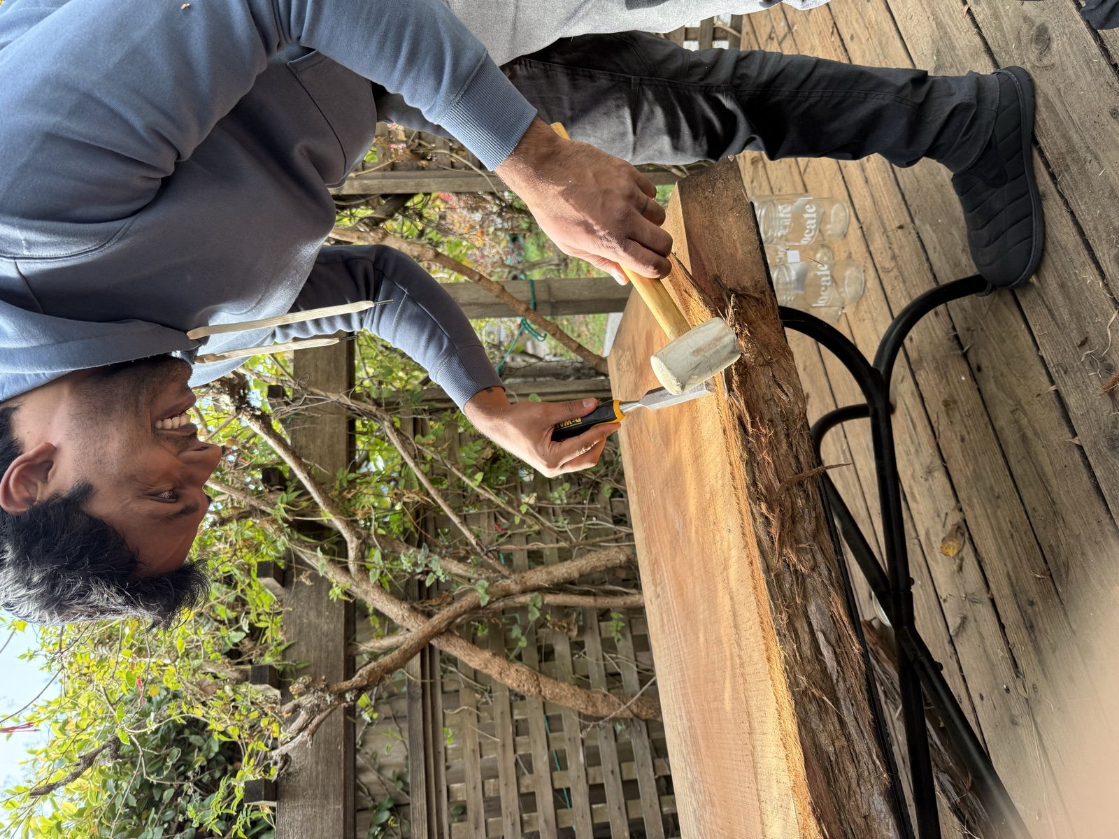 Using a chisel and mallet to pry remaining bark off the edge