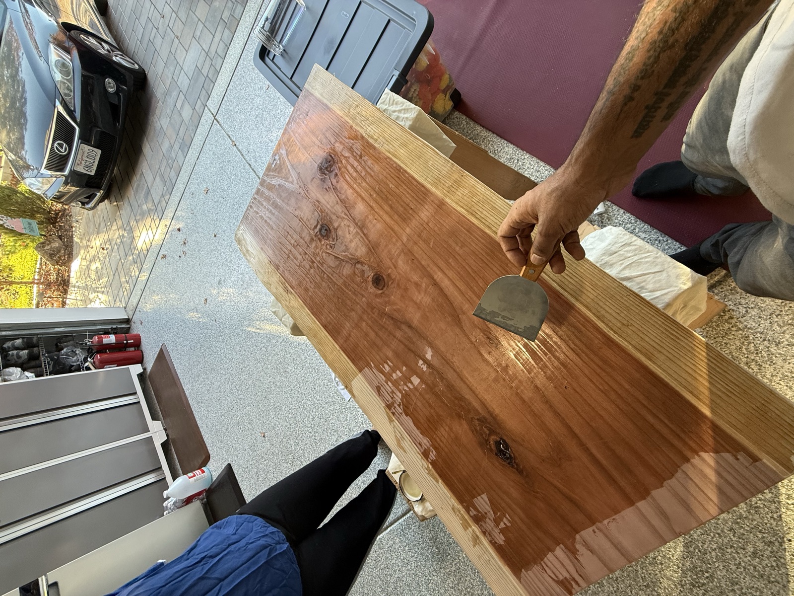 Spreading oil across the slab with a scraper, half the surface still dry