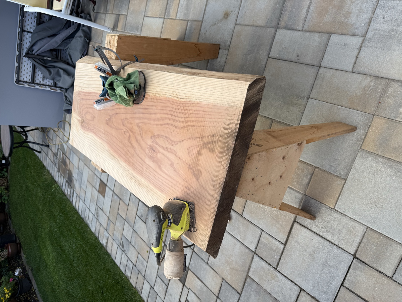 A random orbital sander, safety glasses, and a respirator on the slab mid-sanding