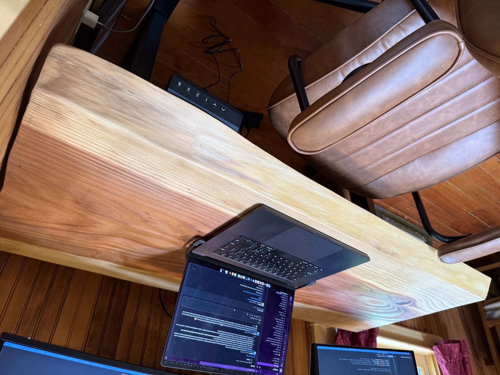 The standing desk from the side, with a laptop open and the height control panel under the right edge