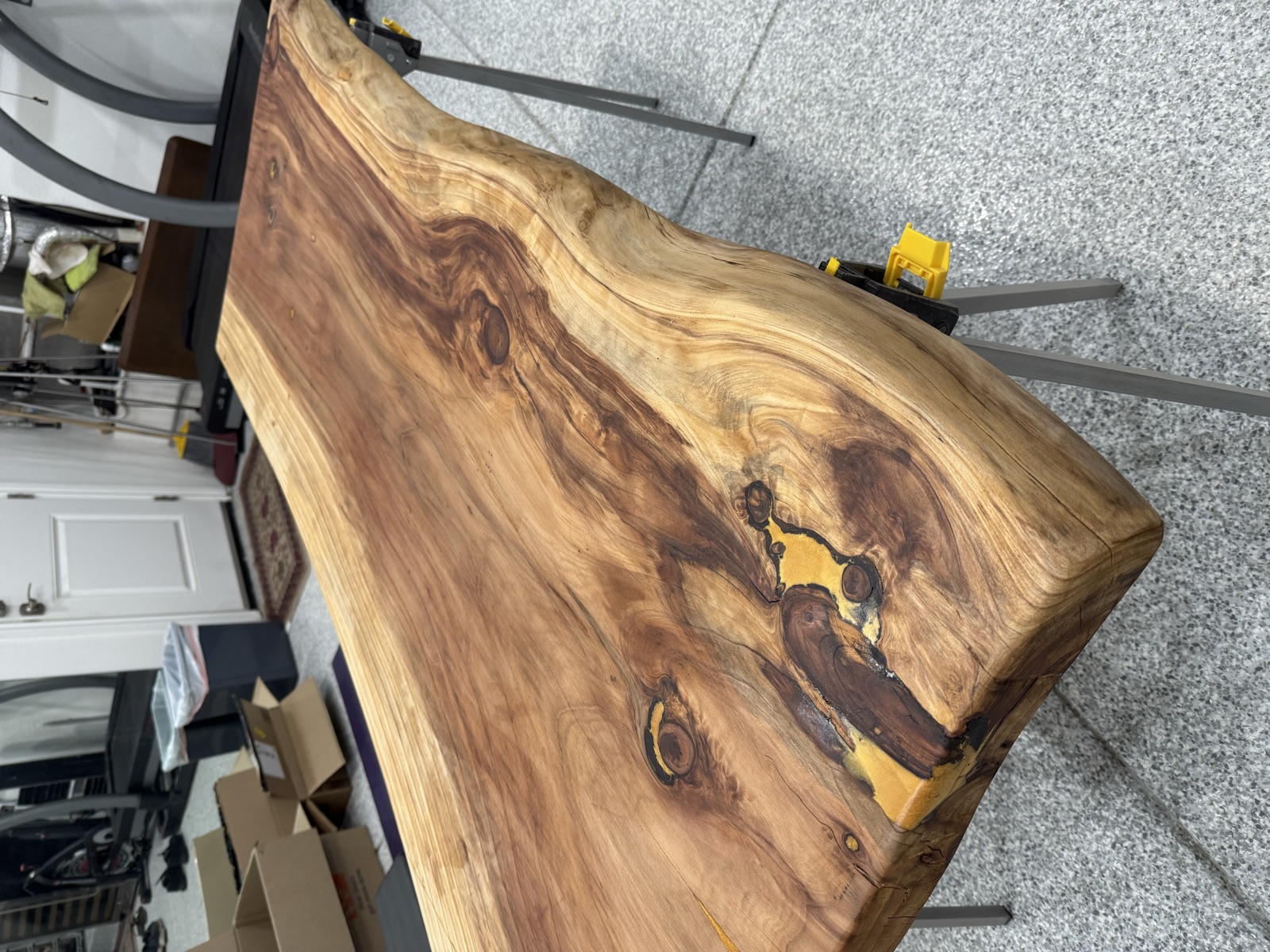 The oiled second slab on sawhorses, with a gold epoxy fill in a knot near the corner