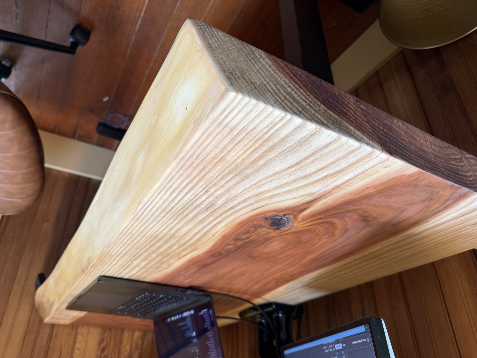 Close-up of the live edge and the thick redwood slab mounted on the black standing desk frame