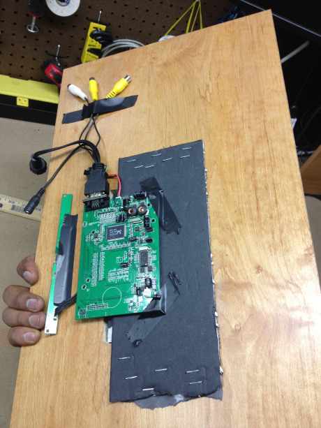 The driver board and ribbon cable laid out on the back of a plywood panel