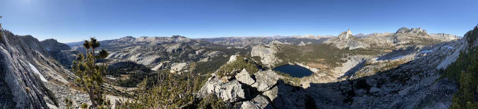 A wide view across granite ridges, an alpine lake, and the valley below