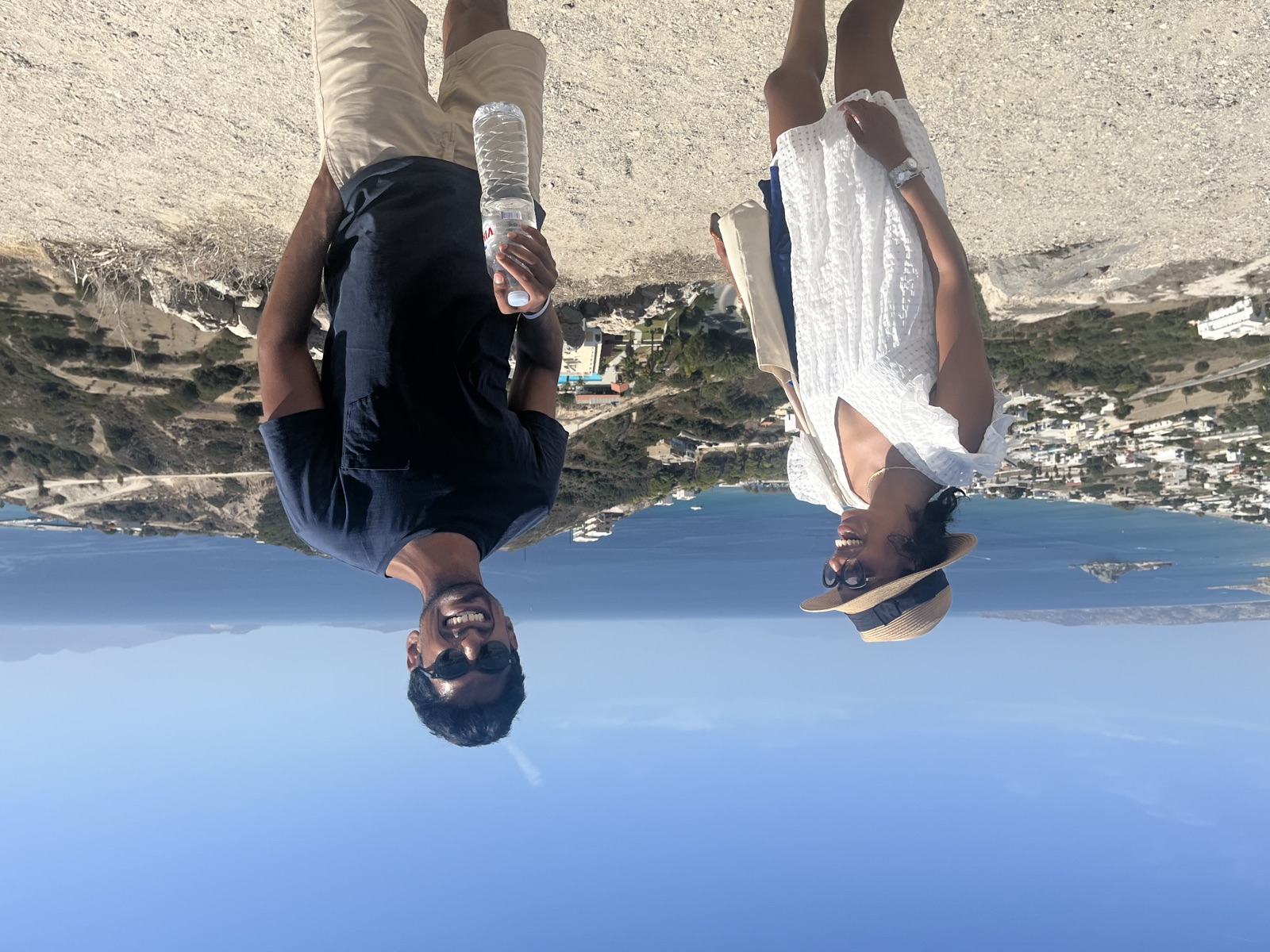 Akhil and Jyo at an overlook above a whitewashed village and the sea
