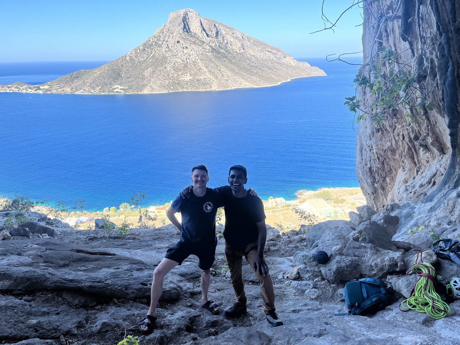 Standing with a climbing partner in a cave, Telendos and the sea in the opening behind us