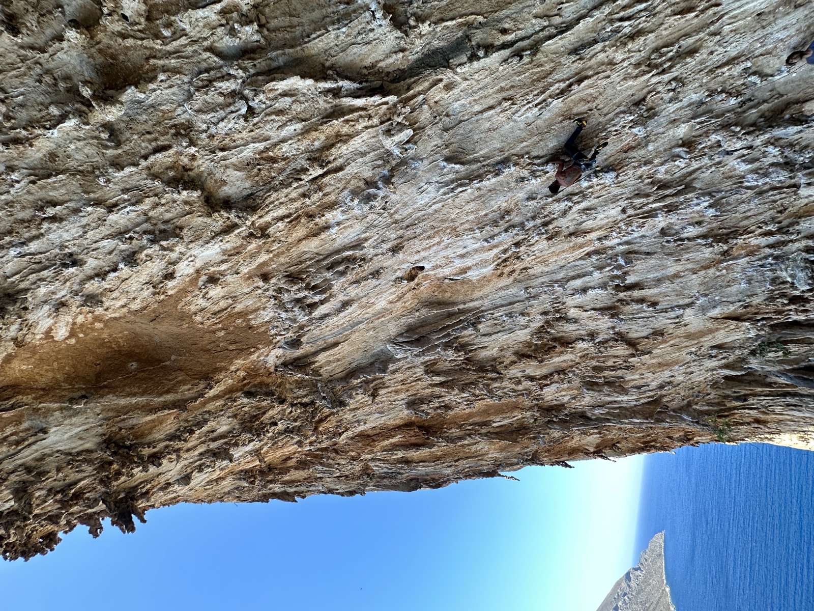 A small figure on the huge tufa wall of DNA, sea on the left