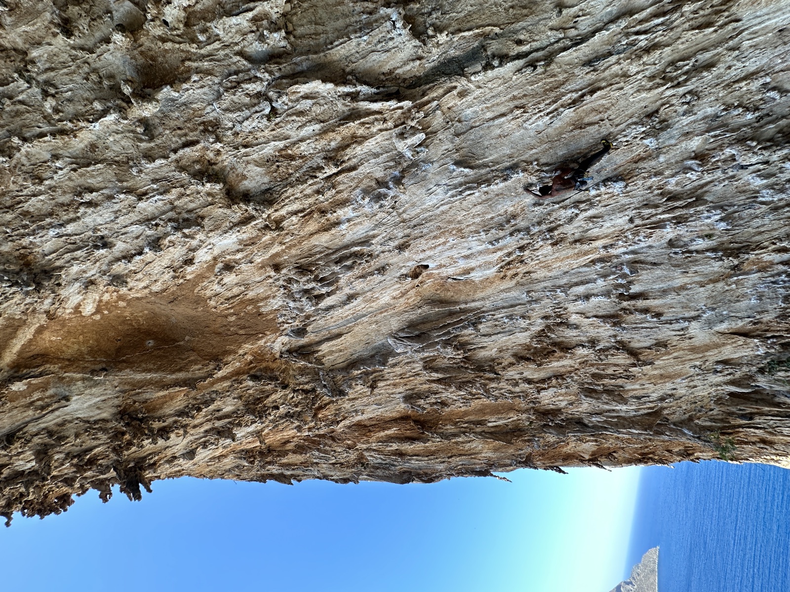 Looking up the overhang at a climber on DNA, coastline in the corner