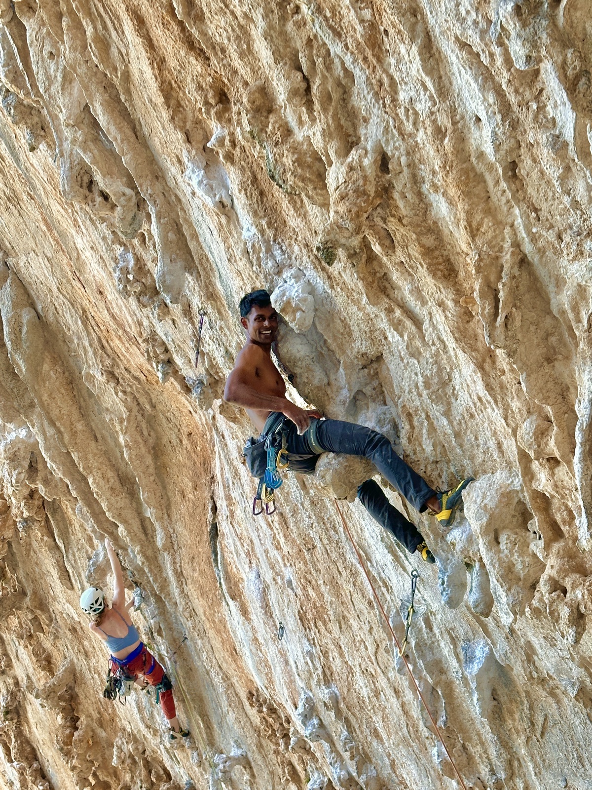Sitting in a tufa rest on DNA, smiling at the camera, another climber below
