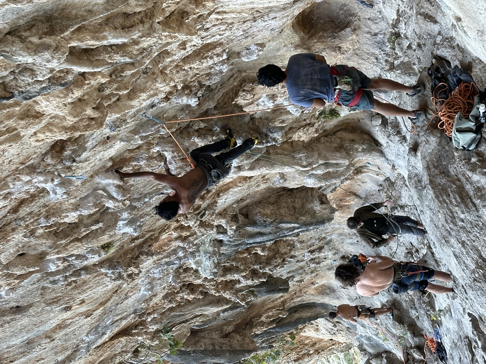 Starting DNA, reaching into the overhang while people belay and watch from the ledge