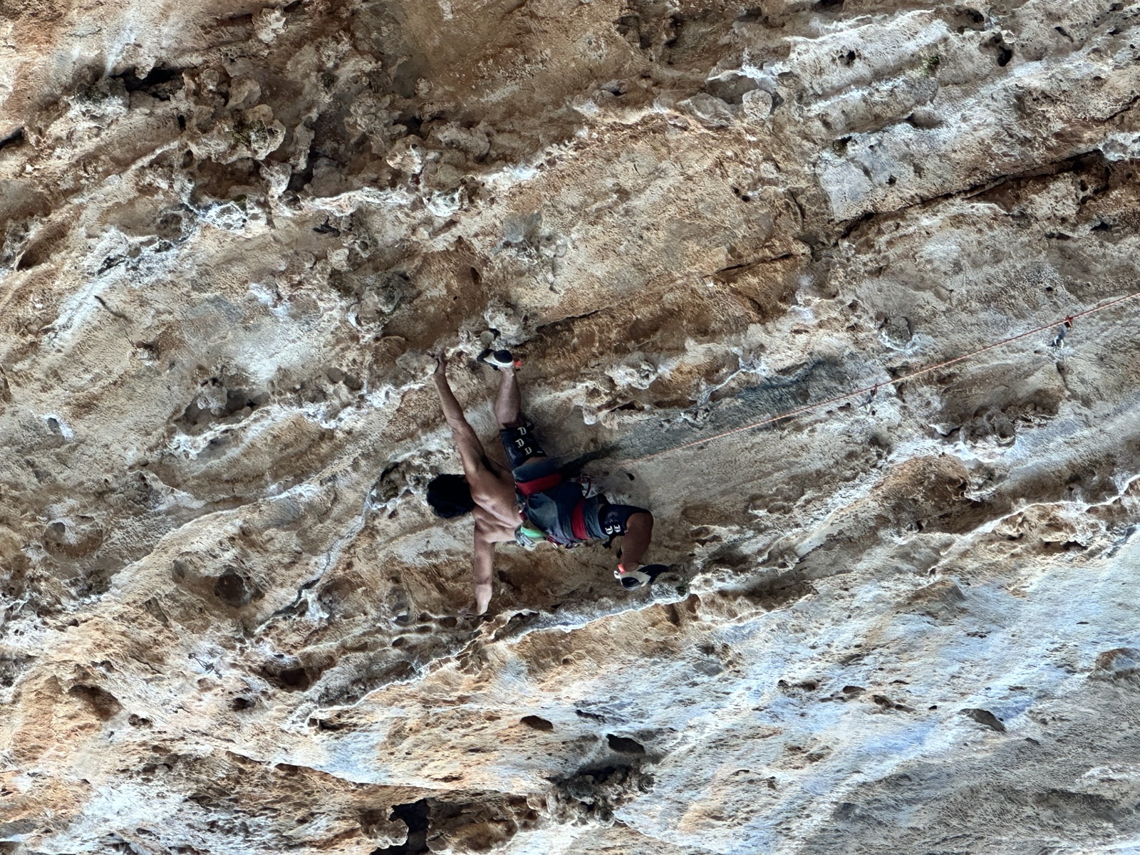 Gabe spanning a steep tufa section with knee pads on both legs