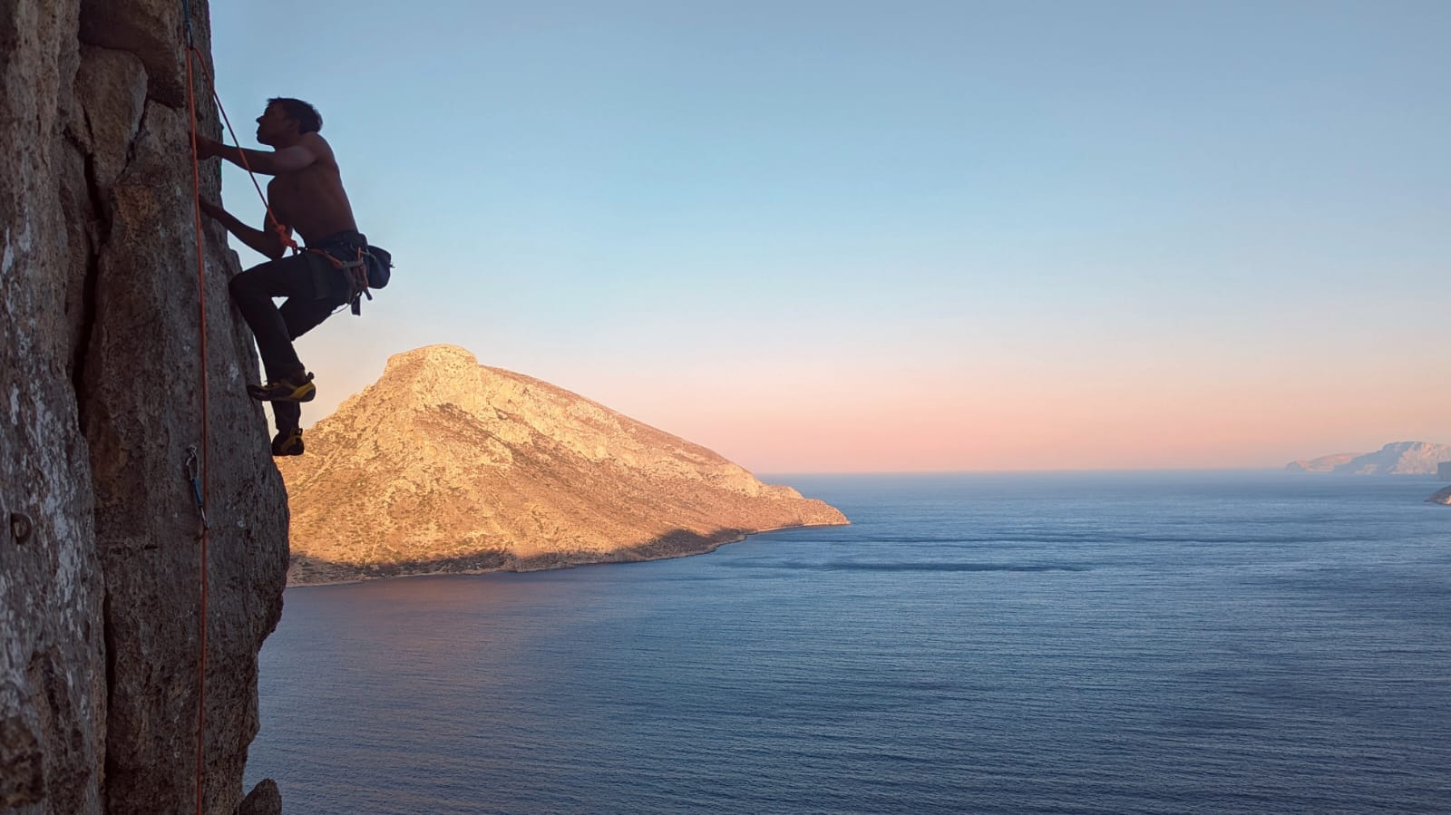A climber on a sunlit limestone face in the morning