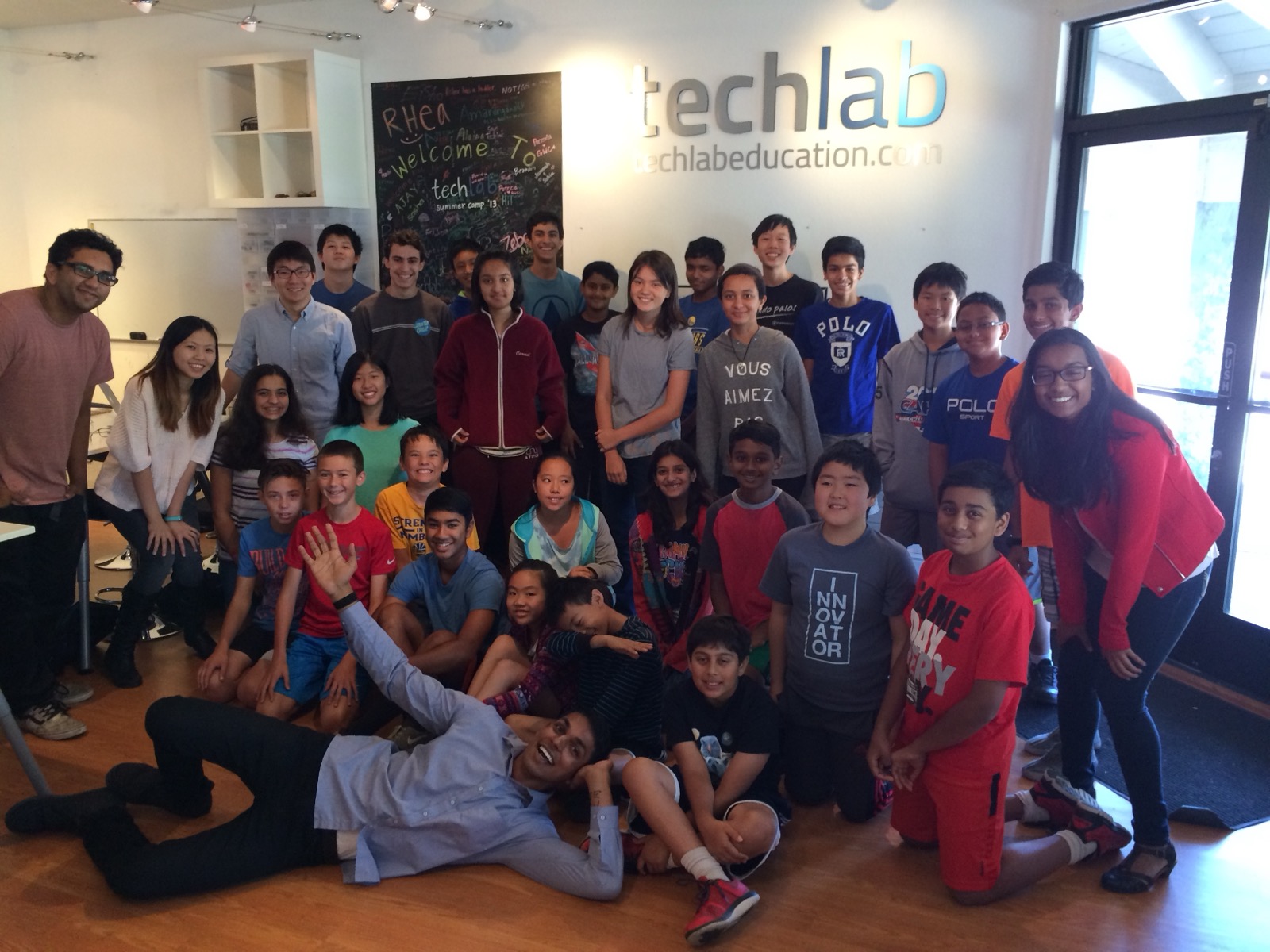 Students and instructors posing in front of the TechLab storefront sign after summer camp